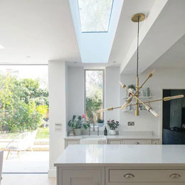 Bright white kitchen with rooflight, window and door